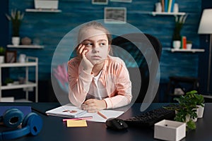 Little girl doing homework feeling bored and sad