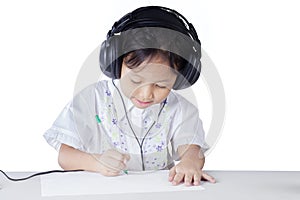Little girl doing homework while wearing earphones