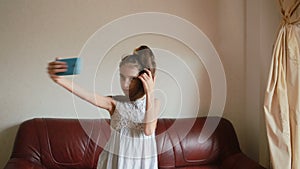 Little girl doing selfie on smartphone at home on couch