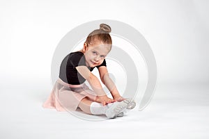 Little girl doing stretching and gymnastic exercises on a white background.