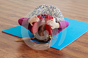Little girl is doing stretching workout on a mat.