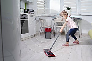 Little girl doing wet cleaning of the floor at home