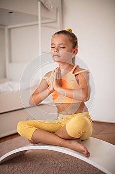Little girl doing yoga exercise at home.