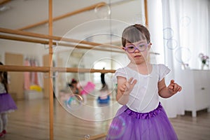 Little girl with down syndrome at ballet class in dance studio. Concept of integration and education of disabled