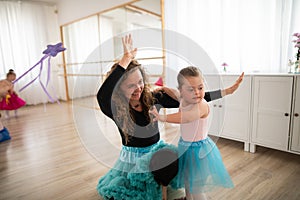 Little girl with down syndrome learning ballet with dance lecteur in ballet studio.