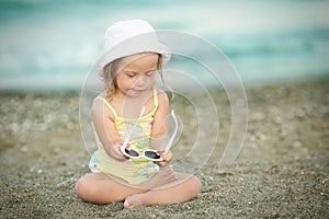 Little girl with Down syndrome playing sunglasses on the beach