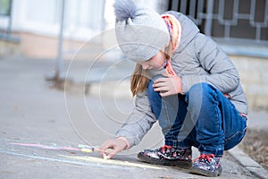 Little girl drawing on asphalt
