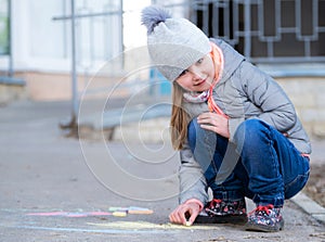 Little girl drawing on asphalt