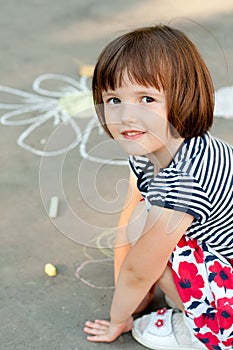 Little girl drawing on the asphalt close-up