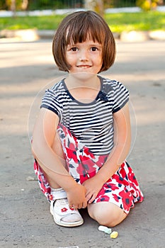 Little girl drawing on the asphalt close-up