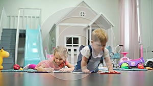 Little Girl Drawing while Baby Crawling Indoors