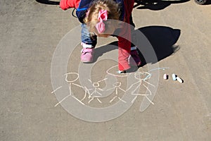 Little girl drawing with chalk on asphalt