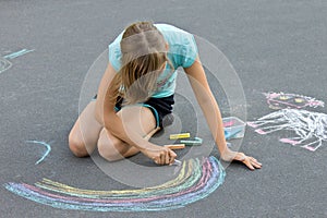 Little girl drawing a chalk on the asphalt