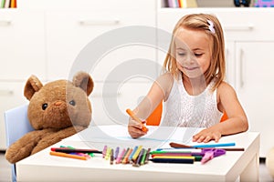 Little girl drawing with color pencils - sitting at the table