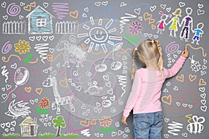 Little girl drawing with colorful chalk on wall