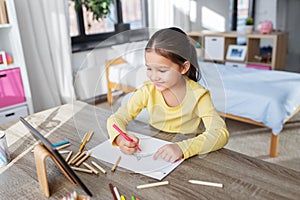 little girl drawing with coloring pencils at home