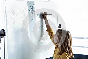 Little girl drawing a eolic park on a whiteboard with a marker pen at home