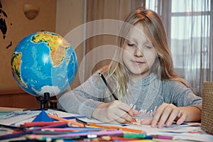 Little girl drawing on her book and having fun at playtable. Child girl does her school homework at home