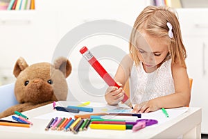 Little girl drawing with a large pencil - sitting at the table