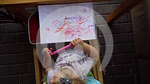 Little girl drawing messily in album