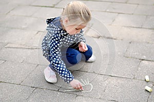 Little girl drawing outside with chalk