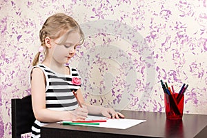 Little girl drawing with pencils at table
