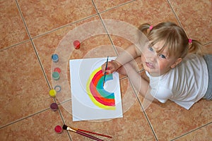 Little girl drawing rainbow. Quarantine fun. Kids paint