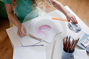 Little girl drawing red heart on paper. Kid childs hands draw painted heart on card for Mothers Day present. Girl draws