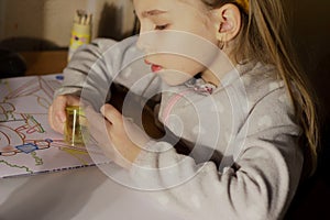 A little girl draws and draws on paper and sharpen a blunt pencil in a sharpener