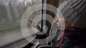 A little girl draws a heart on a fogged window in a traveling bus. View from inside the bus. Blurred background. Closeup