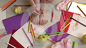 Little girl draws on her feet with felt-tip pens, children`s creativity, development