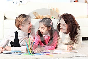 Little girl draws with her mother and grandmother