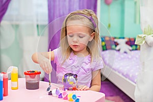 Little girl draws paints at her desk in the room