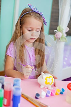 Little girl draws sitting at table in room on her