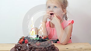 Little girl dreaming and blows out candles