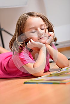 Little girl dreaming while reading a book