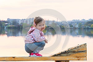 Little girl dreaming sitting on the bench near river