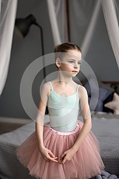 Little girl dreams of becoming a ballerina. Child in a pink tutu dancing in a kids room.