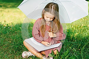 Little girl in dress reading book in park