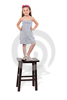 Little girl in dress stands on stool