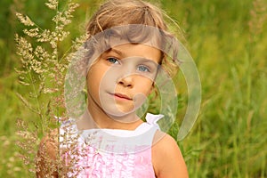 Little girl in dress stands in tall grass