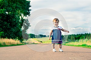 Little girl in dress walking on a country road