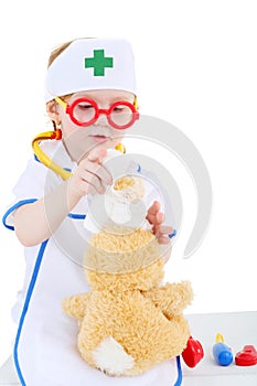 Little girl dressed as nurse bandages head to toy rabbit photo