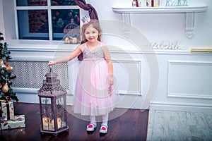 Little girl dressed in beautiful fashion white flower dress posing near Christmas tree