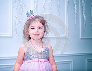 Little girl dressed in beautiful fashion white flower dress posing near Christmas tree