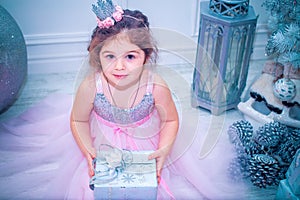 Little girl dressed in beautiful fashion white flower dress posing near Christmas tree