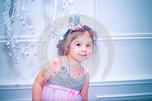 Little girl dressed in beautiful fashion white flower dress posing near Christmas tree