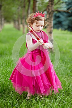 Little girl dressed in bright puffy gown examines photo
