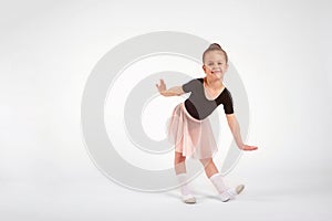 Little girl dressed in dance uniform is dancing over a white background in the studio.