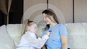 Little girl dressed in medical uniform playing as doctor with mom